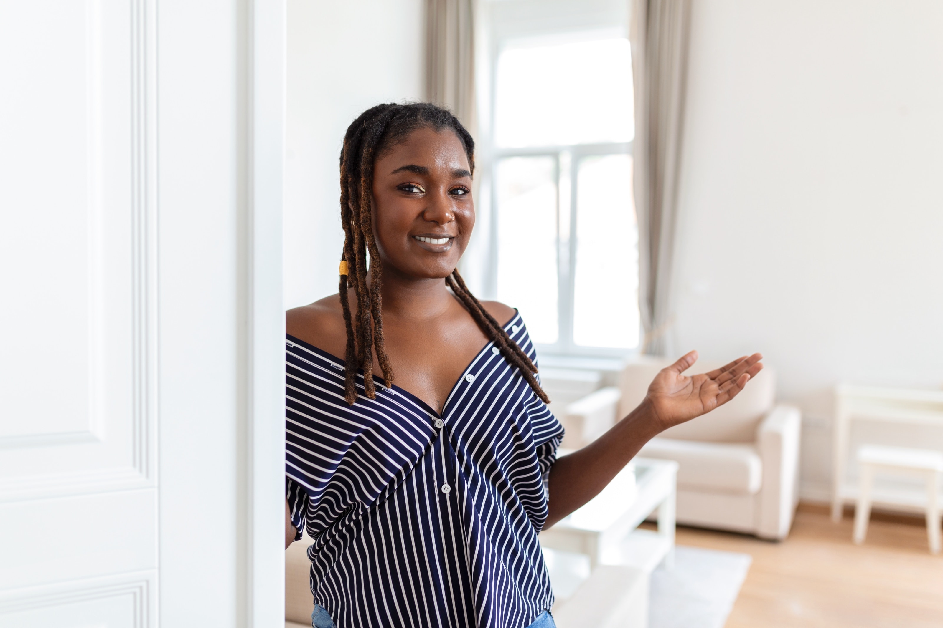 Une femme souriante accueille un visiteur dans un appartement lumineux